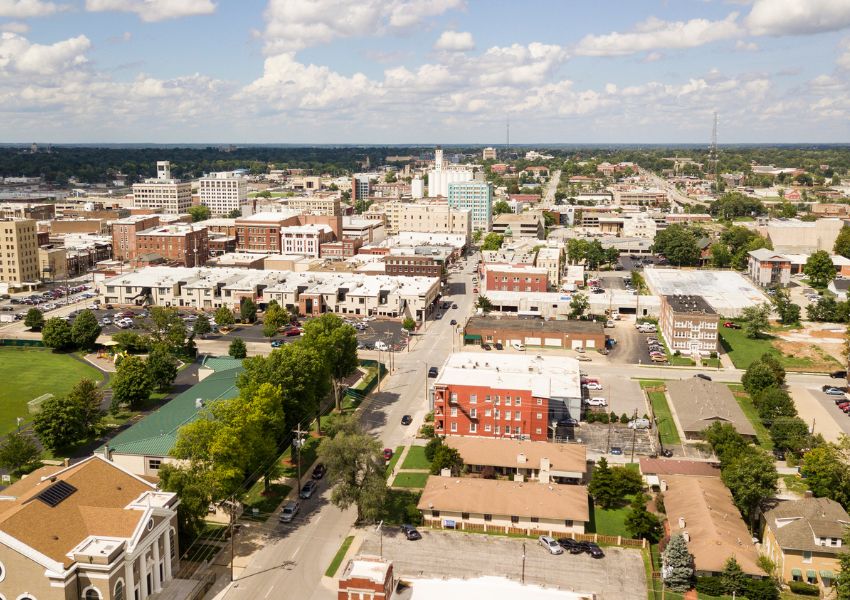 An overhead view of Bryan County is pictured, with urban spaces, brick buildings and cement roads under a blue sky.
